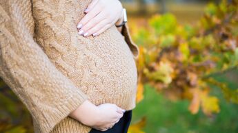 En gravid kvinne holder hendene på magen.