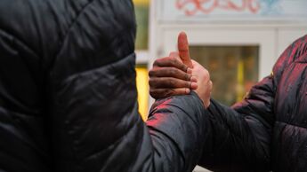 To gutter tar hverandre i henda. En mørk og en lys hånd
