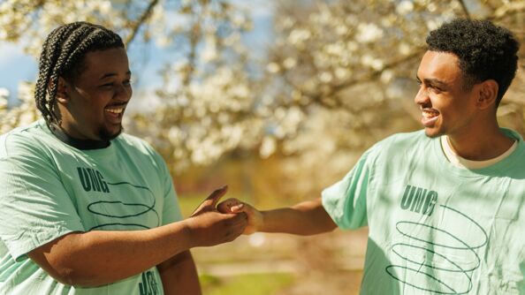 To gutter i ungjobb tskjorte gir hverandre et tøft håndtrykk