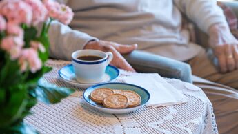 Bilde av en senior og en kaffekopp og kjeks