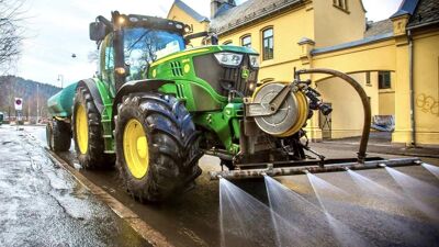En traktor spyler gata.