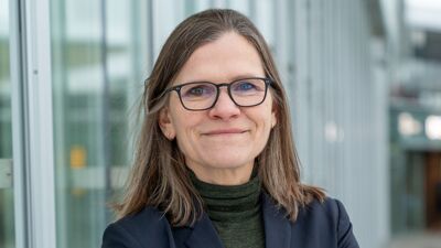 Kvinne i 50 årene med briller og et lite smil