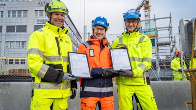 Følgeseddelen fra verdens første leveranse av EvoZero-betong rammet inn og vises frem av Giv Brantenberg, leder for Heidelberg Materials Northern Europe, Stein Ivar Hellestad, CEO i Skanska og Knut Sandbu, teknisk direktør i Fornebubanen.