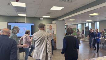 Flere mennesker står spredt rundt i et rom og trener. Noen har ryggen til kameraet, mens andre ser inn i kameraet.