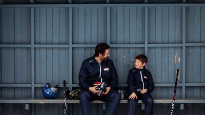 Far og barn sitter på en benk. Det er vinter.