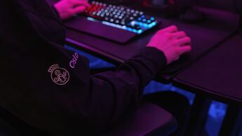 Person sitter foran PC i mørkt rom. Logo til Oslo kommune på jakkearmen.