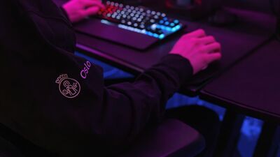 Person sitter foran PC i mørkt rom. Logo til Oslo kommune på jakkearmen.