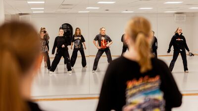 Elever får danseundervisning i en speilsal.