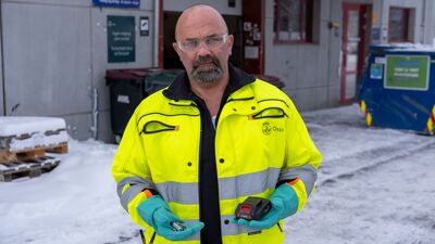 Mann i gul jakke holder batterier