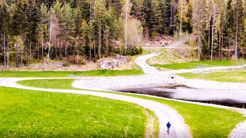 Grusveier og et lite vann foran en skog