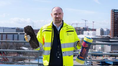 Mann i gul jakke holder jernrør og gassflaske