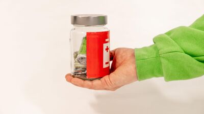 En hånd holder en glasskrukke med batterier