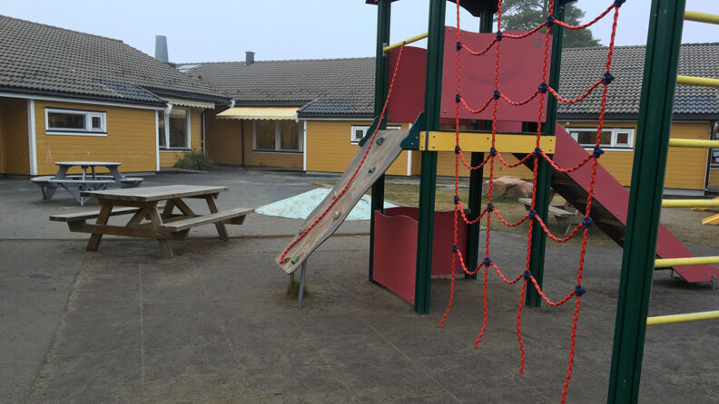 Uteplassen med 2 benker, klatretau og sklie, står på sand