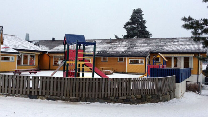 Uteområdet med gjerde rundt, sklie, klatrestativ og 2 benker, om vinteren