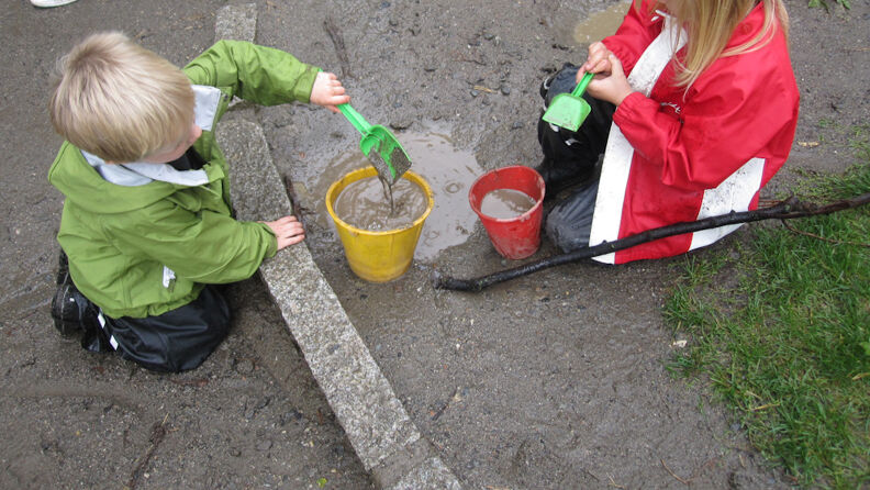 Oskar Braaten barnehage - to barn leker med bøtte, spade og vann i sandkassen