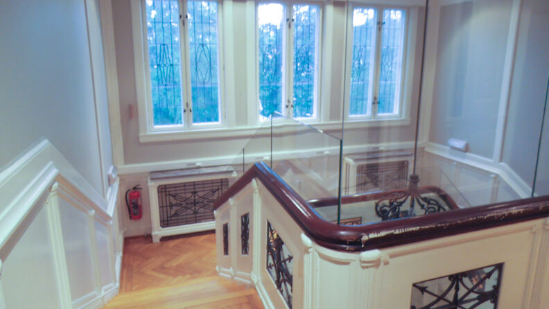 Trapp inne i barnehagen med to vinduer mot trappen, gelenderet er forhøyet med pleksiglass