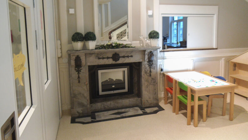 Grå og hvitmalt rom med peis og bord og stoler