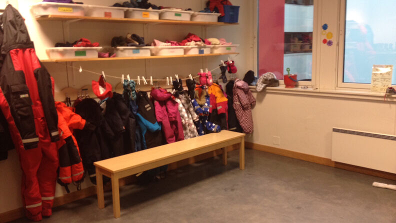 Garderobe med benker og hyller og klær som henger på en snor