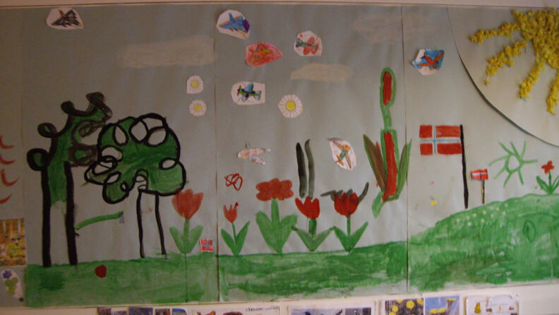 Barnetegning med flagget, solen, blomster og tær, hengende på veggen 