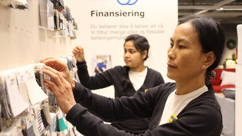 To kvinner med IKEA-navnelapper ser på stoffprøver på IKEA.