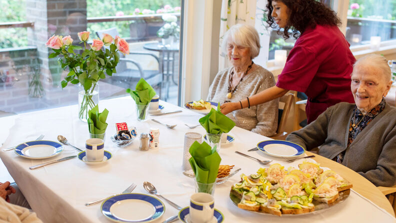 Bilde av beboere som får servert lunsj av en ansatt