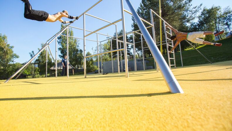 To menn trener kroppsvektøvelser i parkourstativet