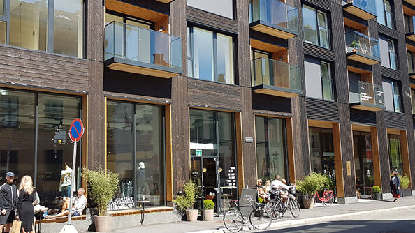 Blokk i bysentrum, næringslokaler med store vindusflater i første etasje, glassbalkonger i etasjene oppover