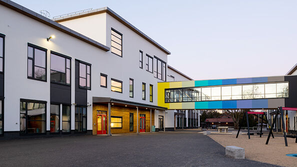 To hvite skolebygg med en fargerik lukket bru mellom