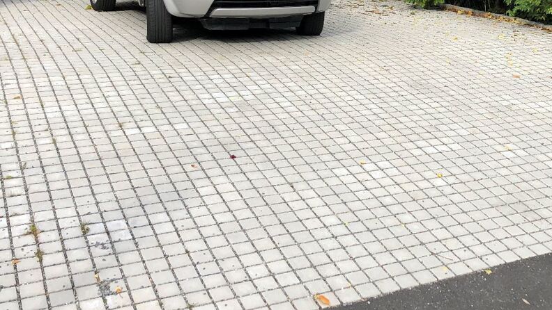 Uteområde med permeabel belegningsstein, parkert bil i bakgrunn
