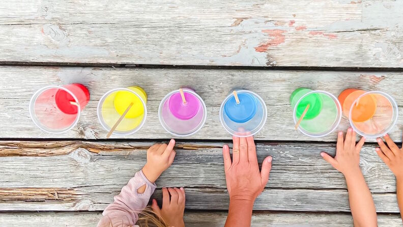 Barn leker med kopper med regnbuefarger