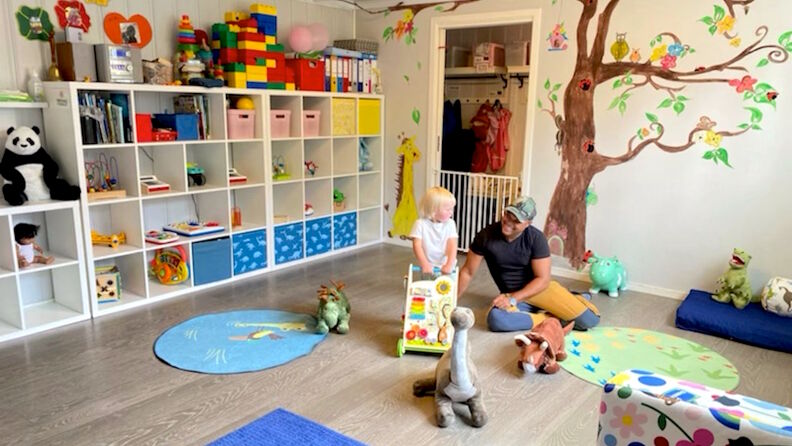 lekerom med hyller med leker, matter på gulvet, tegning på veggen og barn og voksen som leker