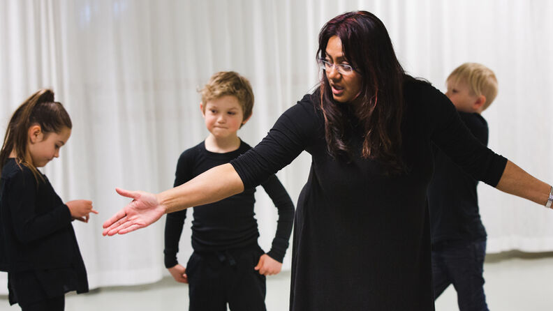 Teaterpedagog står i midten med små barn rundt seg under en teatertime på Schous kulturstasjon.
