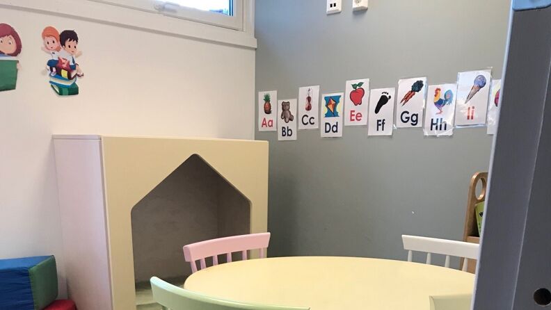 Rom i barnehagen med bord, stoler og bokstavillustrasjoner på veggene