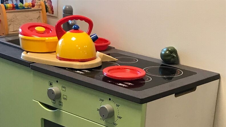 Lekekomfyr i tre og kjøkkenleker i plast inne i barnehagen