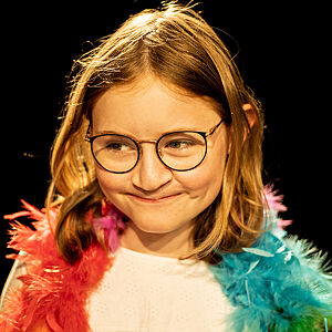 Nærbilde av jente med briller og fargerik boa