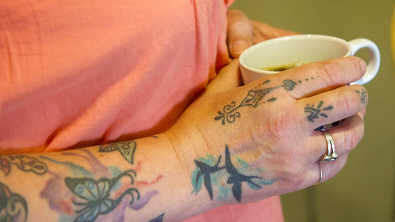 Kaffekopp holdt av kvinne med tatoveringer