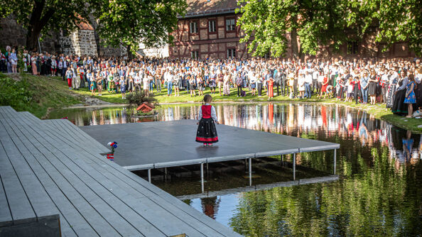 Little girl in Bunad at the 17 May Concert at Karpedammen with a large crowd. 