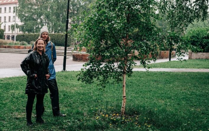 To mennesker som står i regnet foran et tre