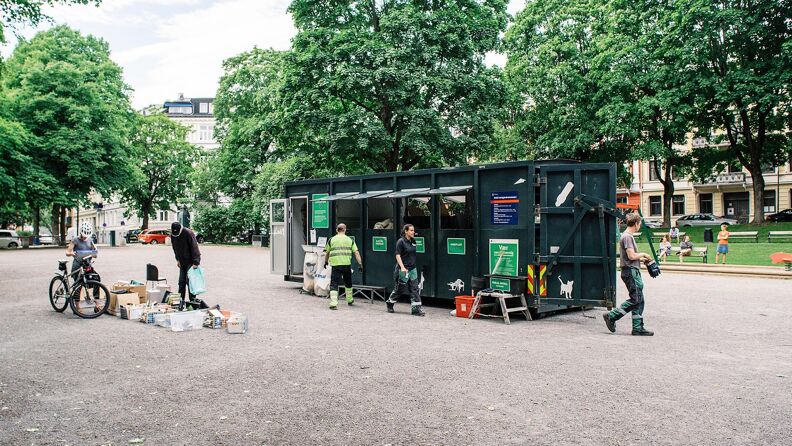 Grønn container på stor plass og folk som kaster avfall
