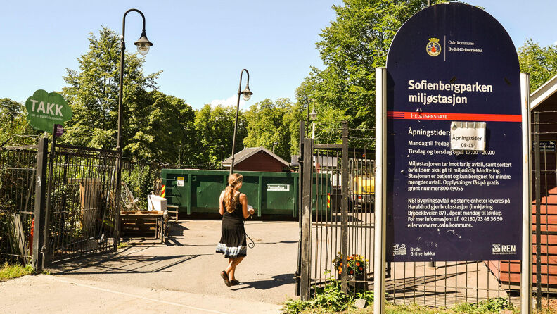 Person går inn en jernport, med et blått skilt foran