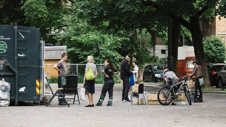 Folk ved siden av grønn container