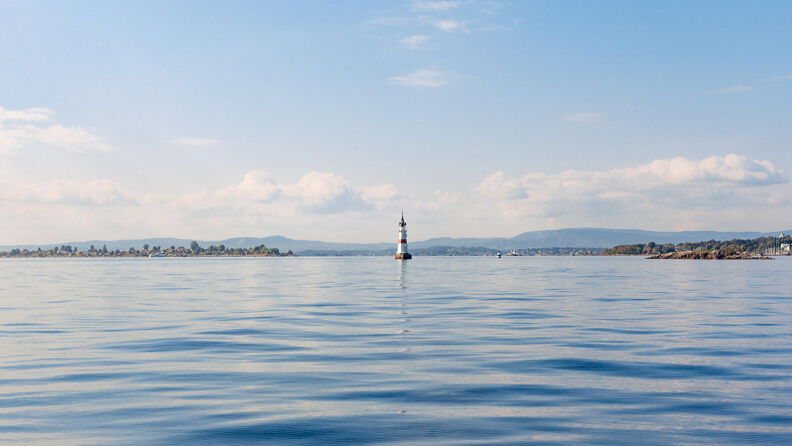 Horisont fra Oslofjorden med en fyrlykt i sommersol.