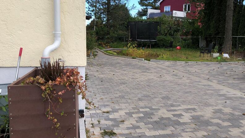 Regnbed foran et hus, uteområde og et annet hus i bakgrunn