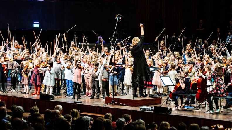 Mange små barn står løfter fiolinbuen på scenen under en konsert i Oslo konserthus.