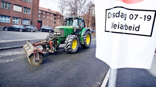 Traktor som børster i gate og midlertidig parkering forbudt-skilt.