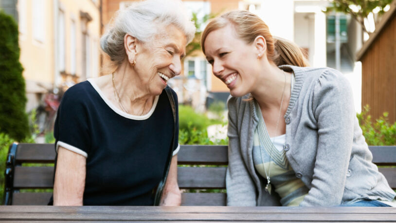 Folkehelse er mer enn trening: Eldre kvinne og yngre kvinne smiler til hverandre på en benk. Foto: Maskot / Oslo kommune / NTB