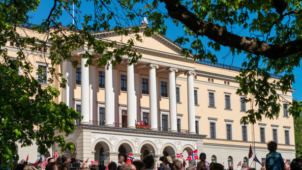 The royal palace with the royal family on the balcony waving to the crowd.