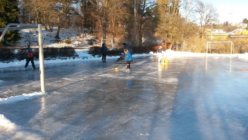 Barn spiller ishockey på skøytebanen i Smestadparken om vinteren.