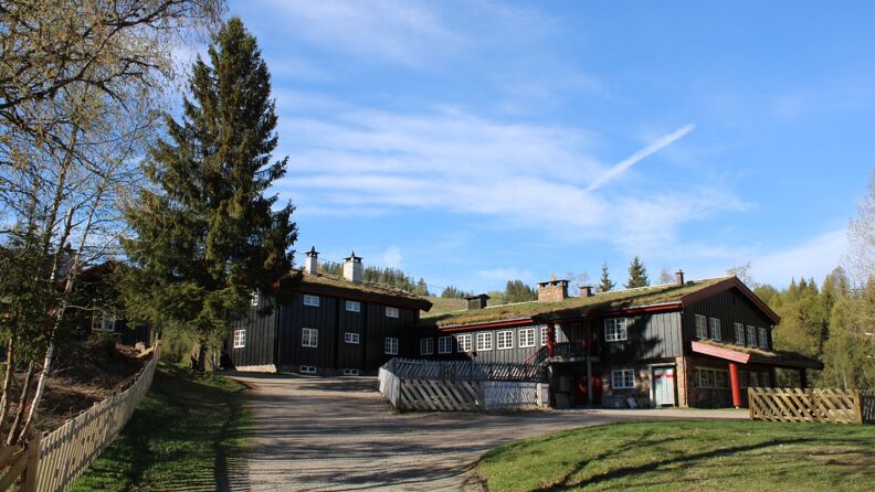 A large lodge at Kikut from the gravel road along the back. It is summer and slightly cloudy. 