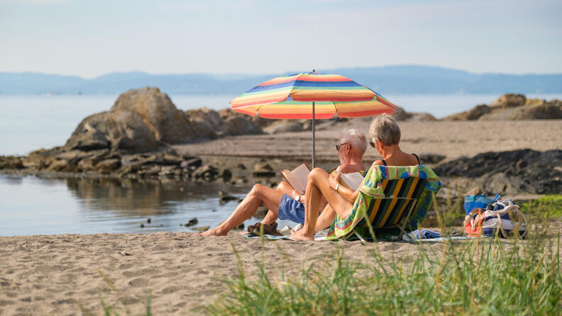 En familie sitter på stranden på Huk